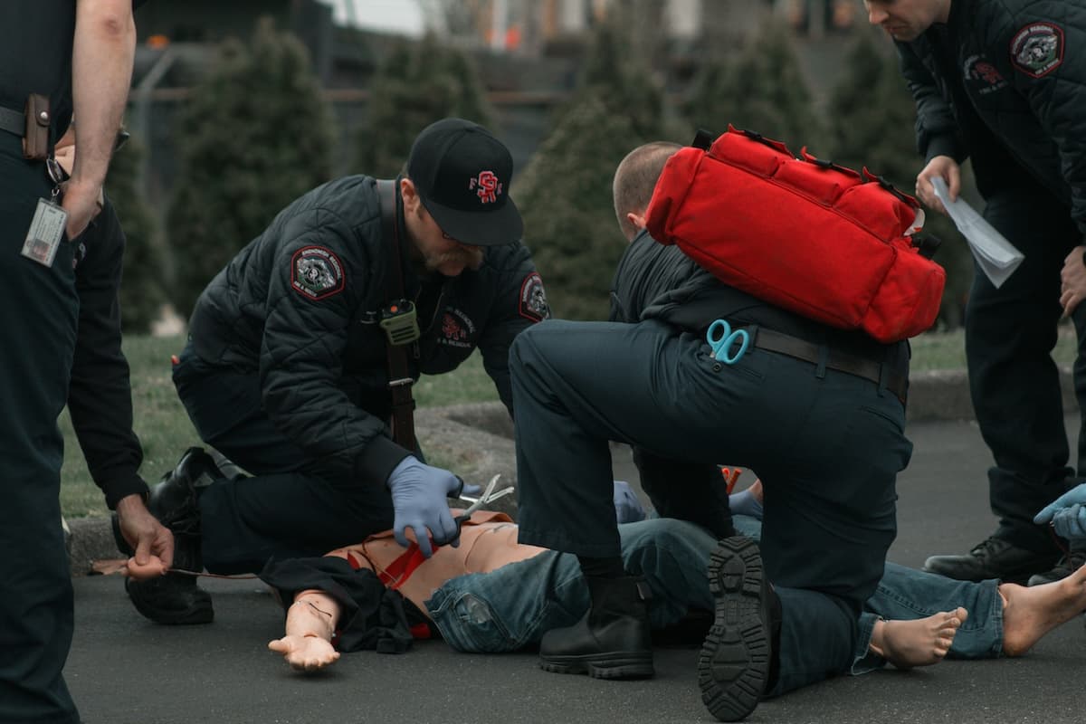 First responders perform emergency medical training on a dummy, simulating a trauma scenario with tourniquet application and field treatment gear.